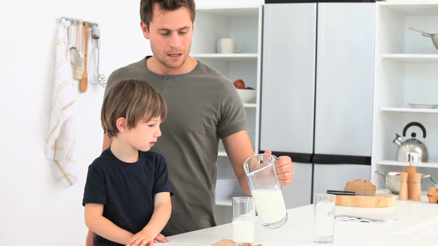 A dad serving a glass of milk to his son