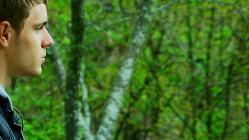 A young man with a camera photographing beautiful green scenery.
