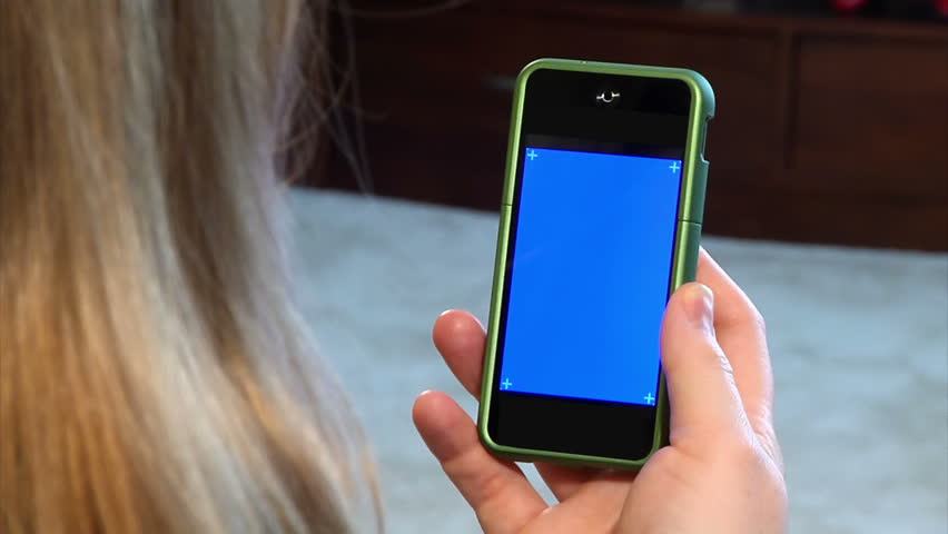 A woman holds a portable cellular telephone.  Bluescreen with corner hashmarks for your own custom screen content.  Luma matte included.