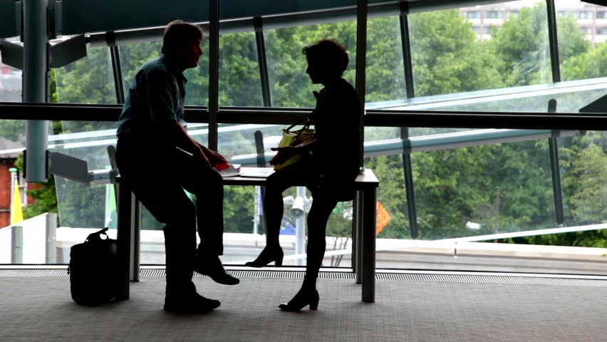 Man and a woman are sitting at the table near the window and talking.