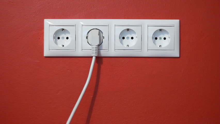 Man unplug and push electric plug into the socket - Closeup of electrical outlets, cable and electric plug on red textured wall