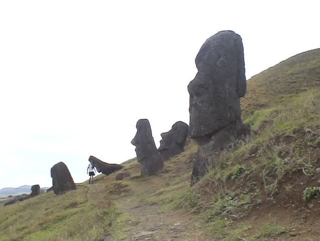 Person walking among ancient Moai Statues on the volcanic slope of Rano Raraku, on Easter Island, South Pacific.