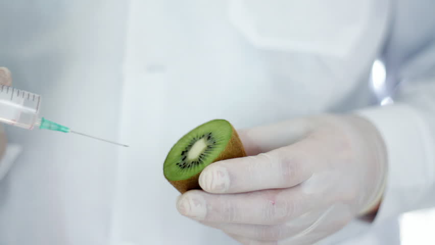 Male scientist hands with syringe injecting kiwi