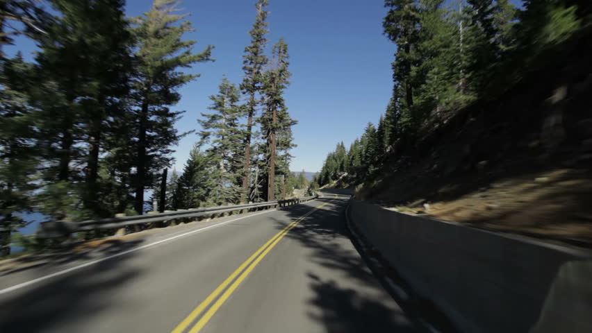 Driving on Emerald Bay Road, high above Emerald Bay on one side, Cascade Lake (not visible) on the other, and Lake Tahoe in the background.