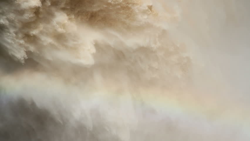 Strong flowing water with water spray and rainbow as water is released from the open sluice gates of a large dam 