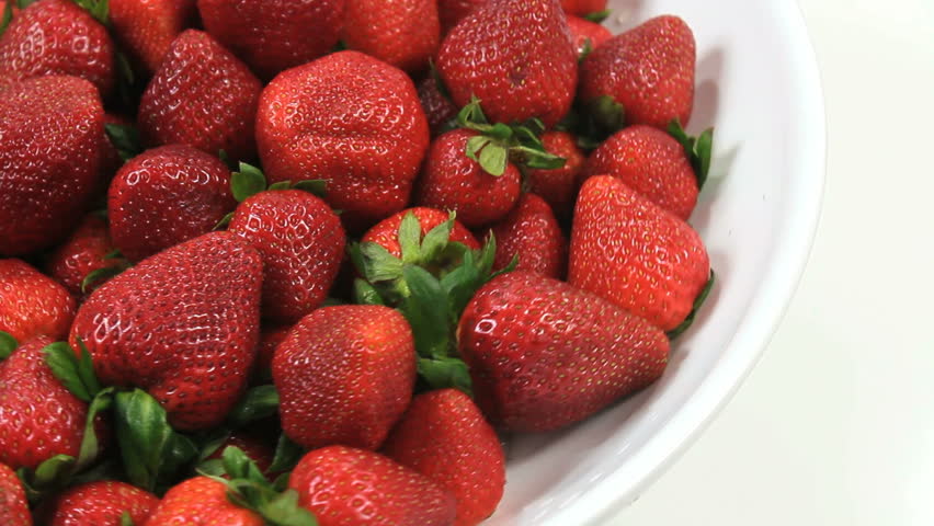 Fresh, ripe, juicy strawberries rotate on white plate against white background. 1080p