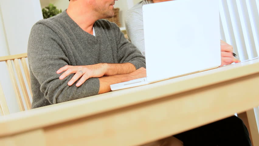 Young caucasian couple at home with laptop computer pleased with the results of their financial planning 