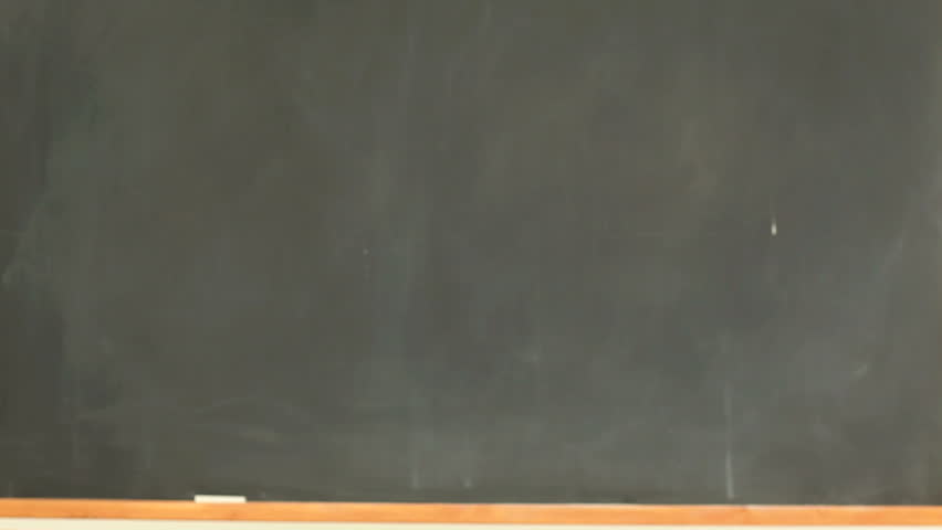 Smiling woman posing while holding some books in a classroom