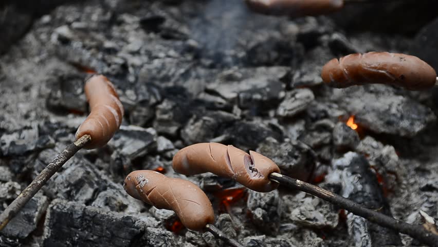 Grilled sausages over campfire