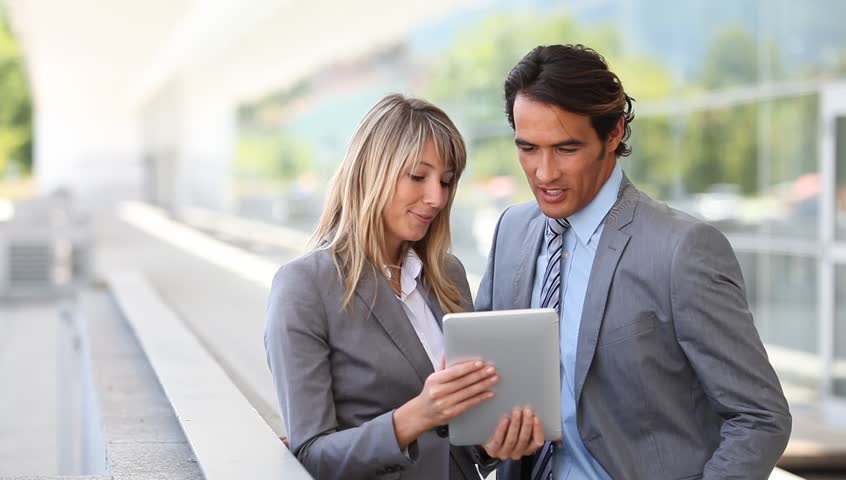 Business team using electronic tablet outside offices building
