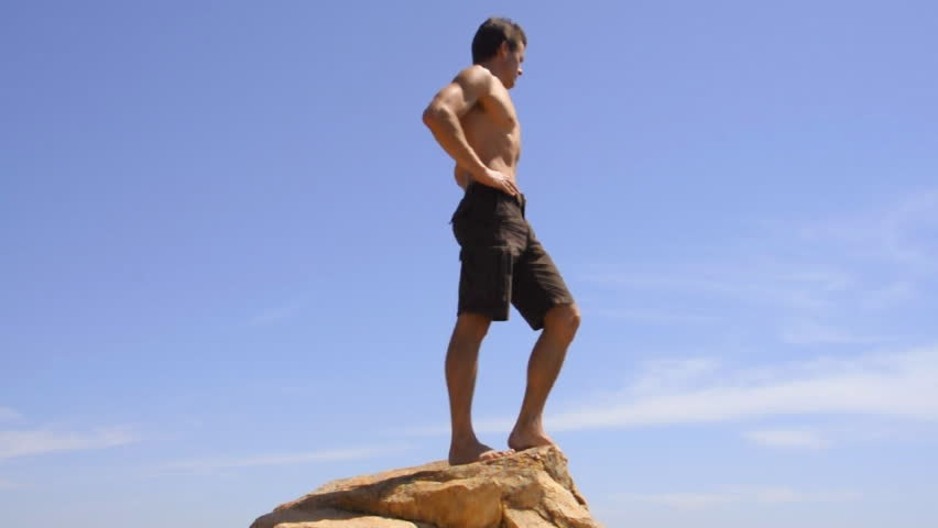 Shirtless adventurous hiker reaches peak and goal