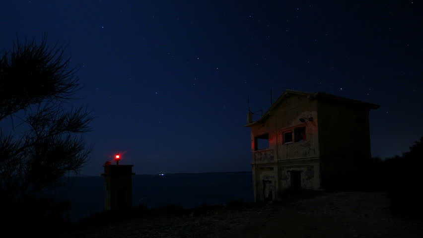 Lighthouse at night with clouds passing in the sky.
