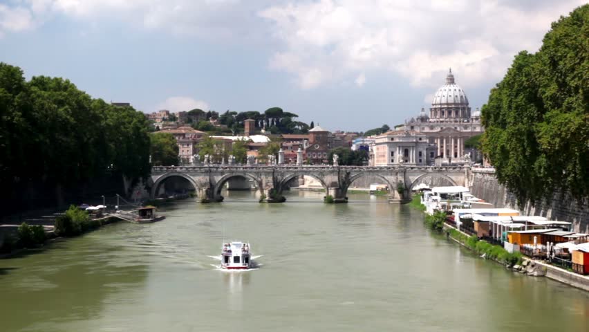 Ship sails on the river against the background of the cityscape with a bridge and the building of Saint Peters cathedral