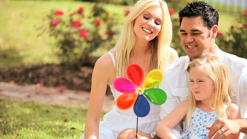 Attractive multi-ethnic family having fun in the park with toy pin wheel