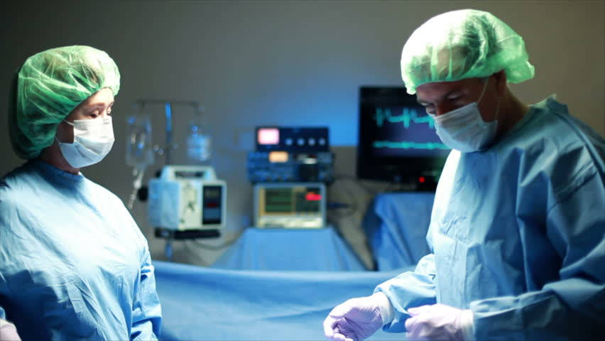 Two surgeons performing surgery are assisted by a surgical nurse.