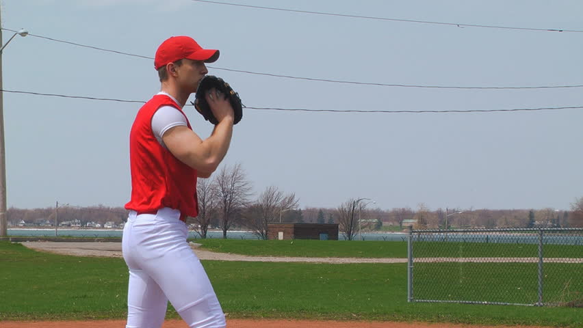 Young adult baseball player at playing field. Pitching. Pan right.
