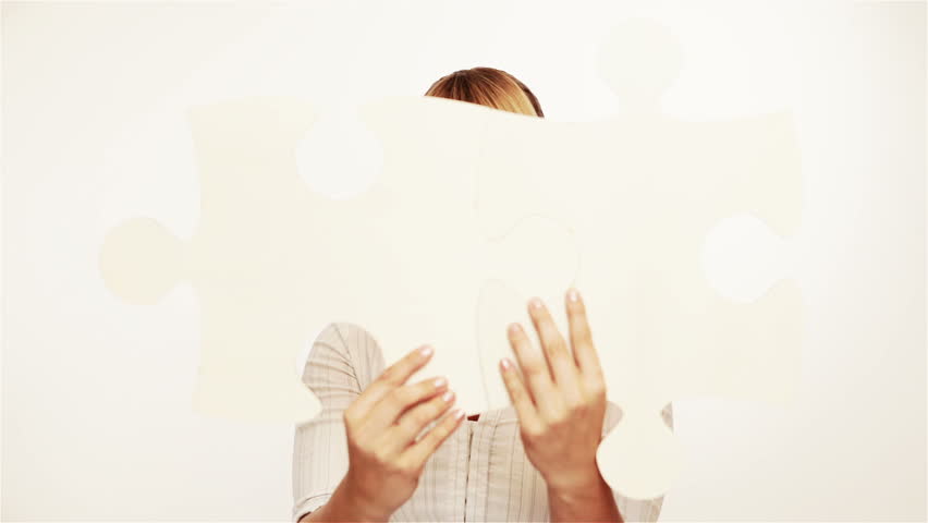 Young woman holding two oversized jigsaw pieces
