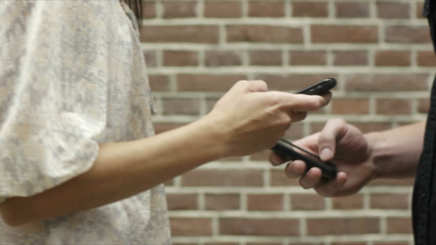 young caucasian couple transferring data on mobile phones via bluetooth connection