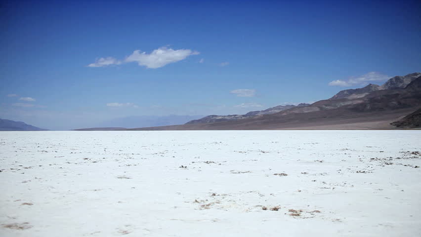 Solitary person walking across the barren environmental landscape of a dry salt lake