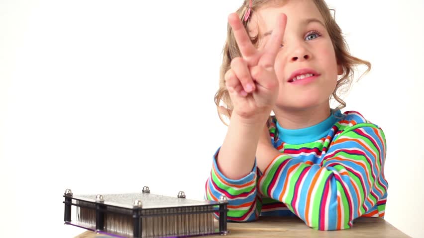 Girl make imprint of two fingers up on pin board of imprint toy