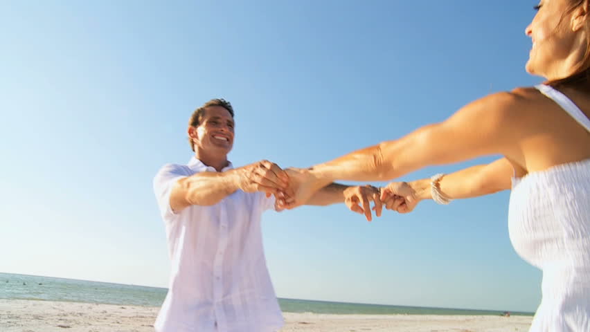 Attractive healthy couple having fun together dancing  on the beach filmed at 60FPS