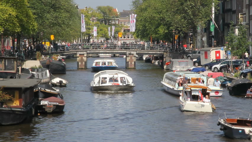 AMSTERDAM, HOLLAND - AUGUST 1: Tour boats sail in busy Amsterdam canal August 1, 2011 in Amsterdam, Holland. The 17th-century canal ring area is on the UNESCO World Heritage List.