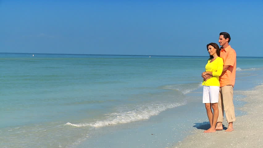 Portrait of an attractive heterosexual couple standing close to each other on the beach filmed at 60FPS