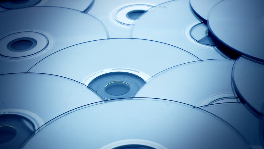 Dolly shot over a stack of blue tinted compact discs