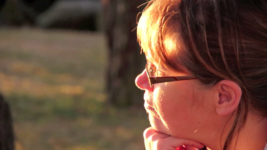 Profile close up of middle aged woman looking ahead then away at sunset.