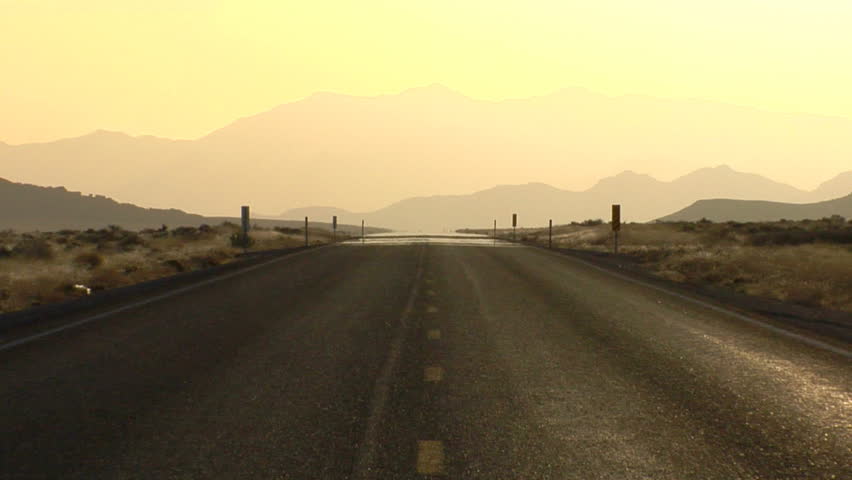 Pull back on a lonely rain wet road heading to distant mountains.