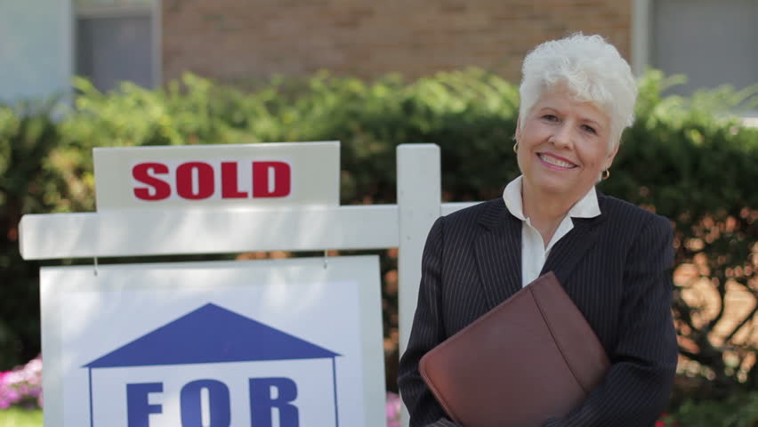 Real estate agent in front of a sold house