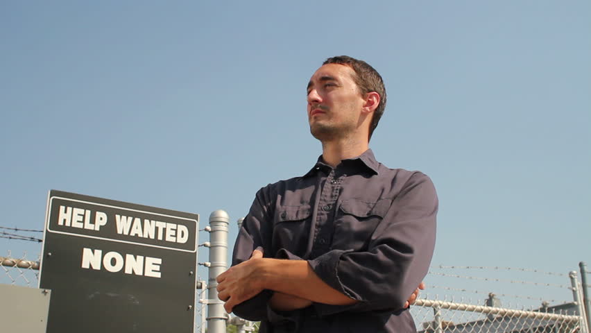 Blue collar worker unemployed outside of industrial building