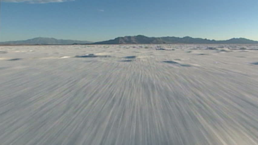 Camera flies low over eerie, dramatic moonscape salt flats.