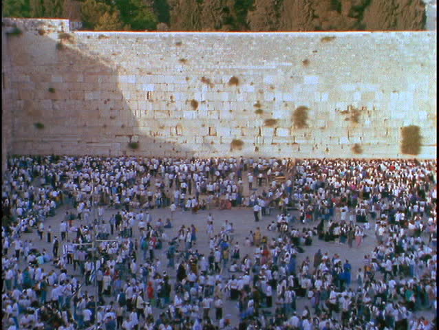 A crowd of people mills about at thee Wailing Wall in Israel.