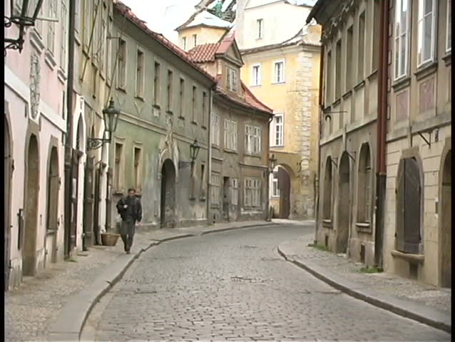 PRAGUE, CZECH REPUBLIC - CIRCA 2010: A medium shot of a man walking along a cobblestone street circa 2010 in Prague, Czech Republica.