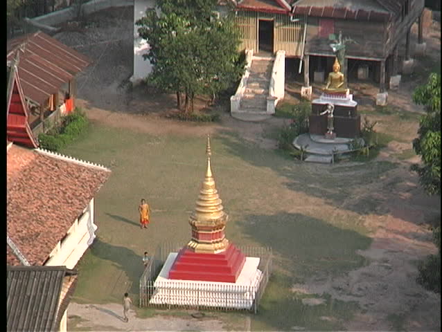 Buddhist Monks walk around a courtyard in an Asian community, in this birds-eye view.