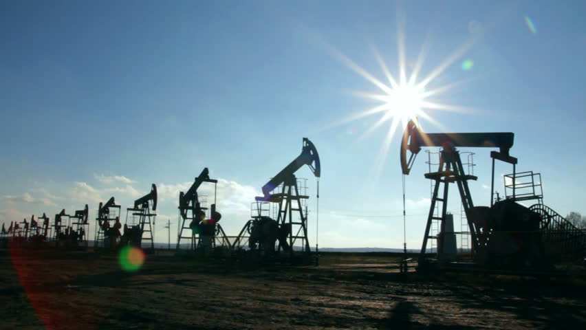 working oil pumps silhouette against sun - timelapse