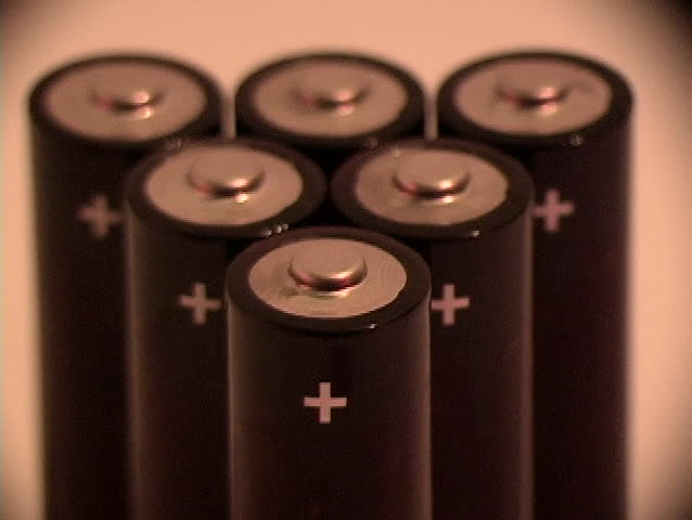 Rack focus and tilt up to reveal six batteries for a portable electronic device.