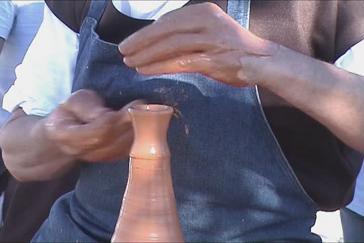 Potters hands creating a clay vase on the turning wheel