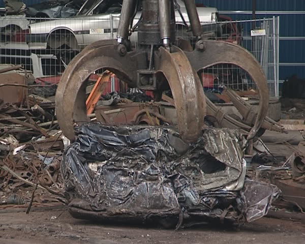 Pressed piece of car handling with special machine. Scrap metal. Industrial junk. 