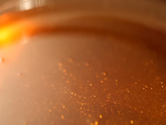 Honey pouring from stick into the bowl.