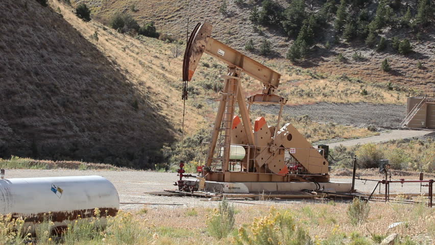 Oil well pumping crude from deep valley between mountains in central Utah. Propane motor powers the pump that extracts the oil.