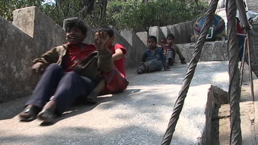 KATHMANDU, NEPAL - CIRCA 2005: Children play and smile while sliding down a cement slope circa 2005 in Kathmandu.