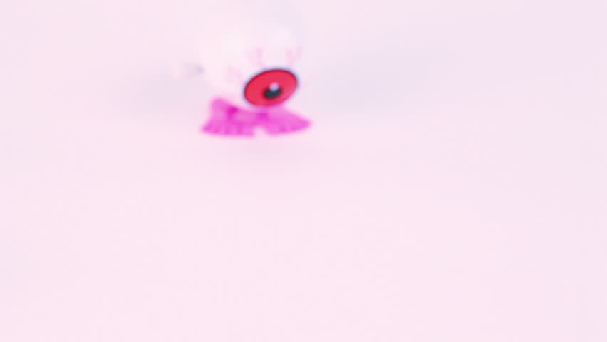 Finger push clockwork toy veiny eye from above and it begin jump away from screen