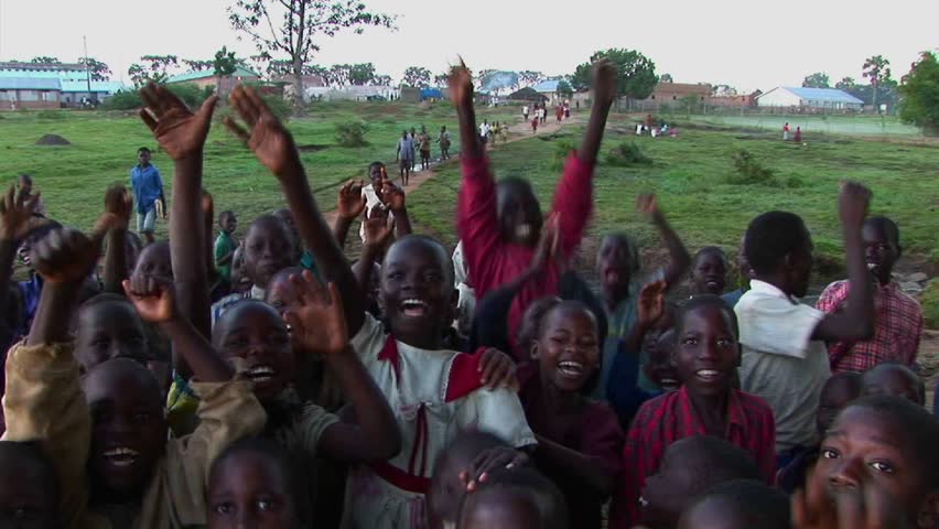 UGANDA, AFRICA - CIRCA 2009: Crowd of children at a refugee camp wave at the camera circa 2009 in Uganda.