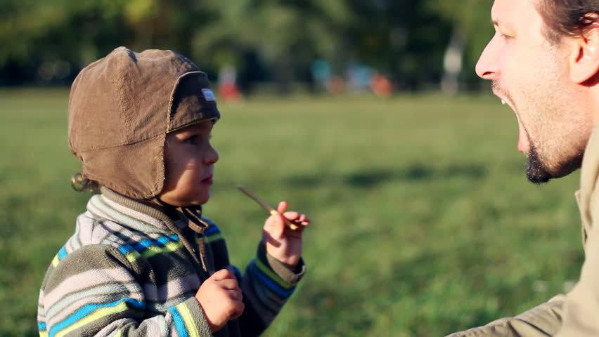 Young child feeding his father with snack, outdoors