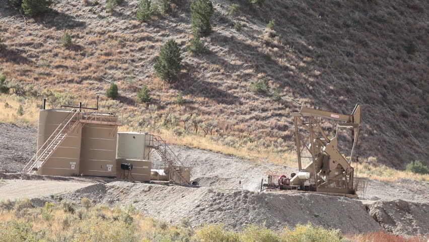 Oil well pumping crude from deep desert valley between mountains in central Utah. Propane motor powers the pump that extracts the oil.