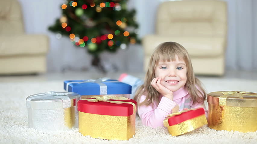 Child with a  gifts lying on the carpet. Looking at camera 