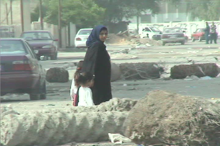 BAGHDAD, IRAQ - CIRCA 2009: A veiled woman leads her children through the streets of Baghdad during the Iraq war.