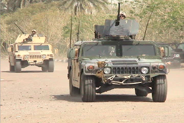 US Army armored Humvees head down a road in Iraq.